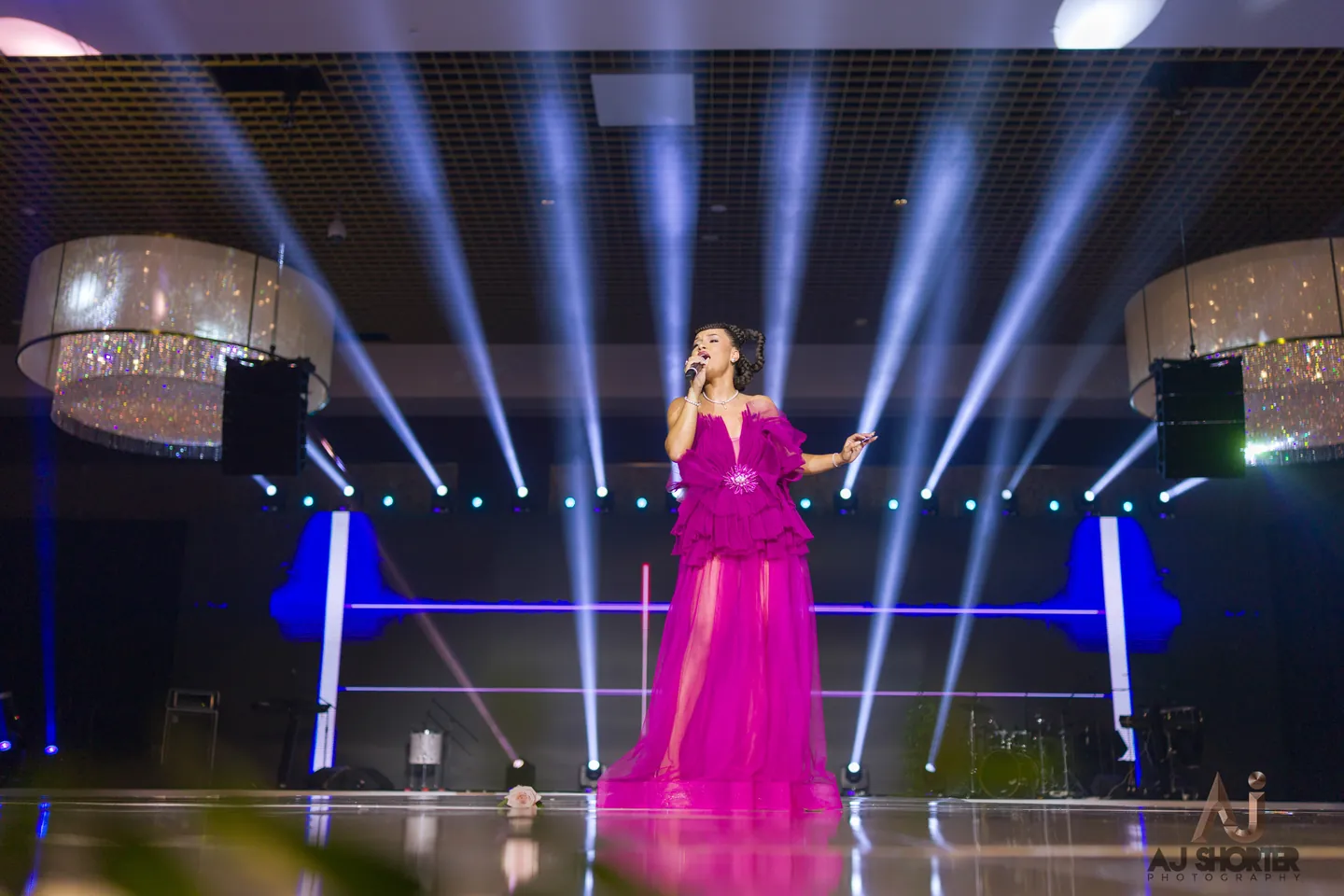 Performer on a gala stage surrounded by beams of light